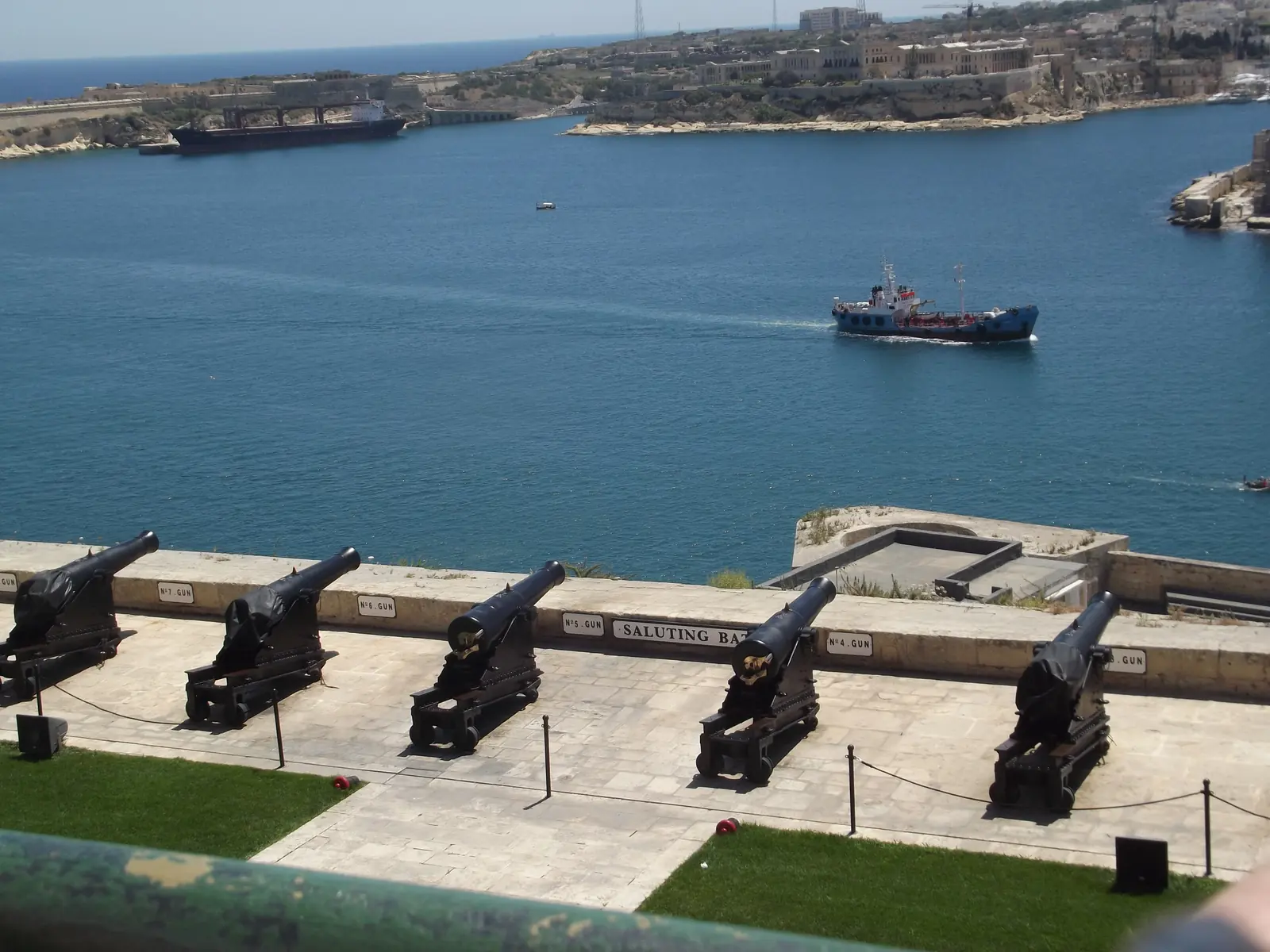 The Saluting Battery cannons in Valletta above the Grand Harbour, with a ship crossing the blue water